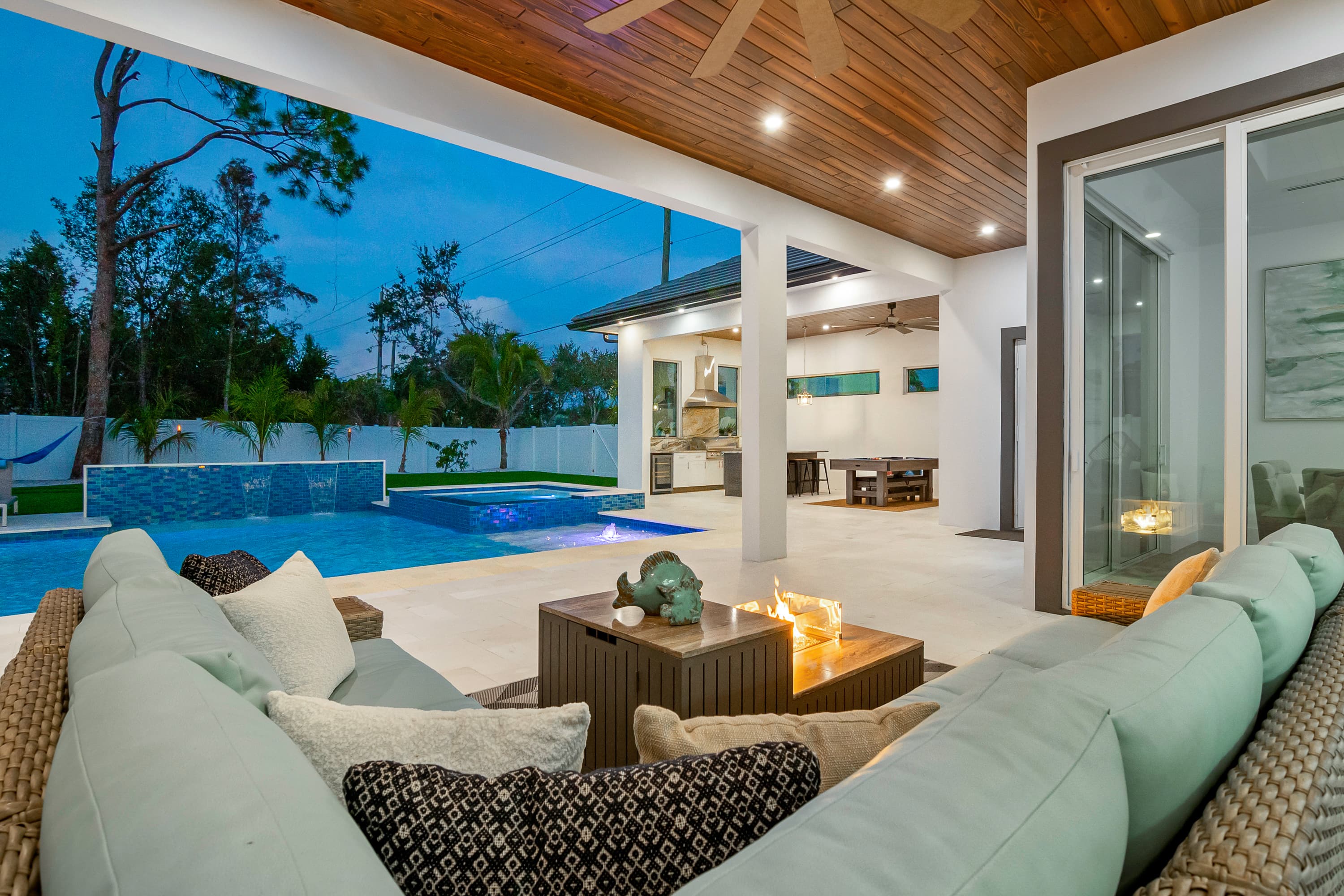 Outdoor lounge area with sofa, built-in fire table, pool, and covered patio ceiling with lighting